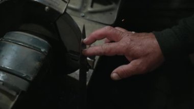 Çelik metal ve demir için pürüzsüz ekipmanlarla öğütme işi. Atölyedeki kıvılcımlara yakın çekim. Öğütme makinesinde araçlar işleniyor