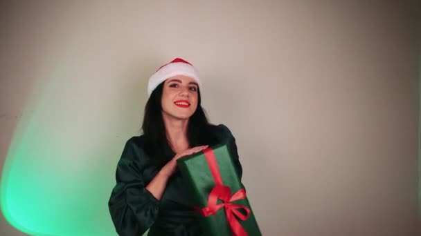 サンタス アシスタントの赤い帽子をかぶった長い髪の少女 クリスマス広告 冬休みについて 新年の贈り物 お祝いの雰囲気 — ストック動画