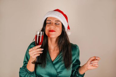 Noel Baba 'nın asistanı kırmızı şapkalı esmer bir kız. Noel reklamı. Kış tatili. Ellerinde bardakla güzel bir kız