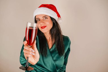 Noel Baba 'nın asistanı kırmızı şapkalı esmer bir kız. Noel reklamı. Kış tatili. Ellerinde bardakla güzel bir kız