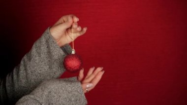 Kırmızı bir Noel balosu yeni yılın ve Noel 'in sembolü gibidir. Kadın eli Noel ağacı oyuncağını tutuyor. Kız neşeli bir ruh hali veriyor. Ejderhanın yeni yıl sembolü. Şenlikli atmosfer