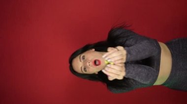 Güzel esmer kız kırmızı arka planda güzel bir konfeti içinde dans ediyor. Tatil kavramı, eğlence, kutlama. Yeni yılı ya da doğum gününü kutluyoruz. Mesaj için yer. Reklamcılık