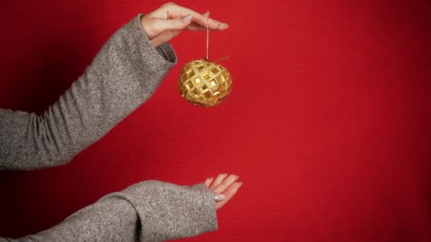 金色的圣诞舞会就像新年和圣诞节的象征 雌性手拿着一个圣诞树玩具 这个女孩给人一种节日的气氛 龙的新年象征 节日气氛 — 图库视频影像