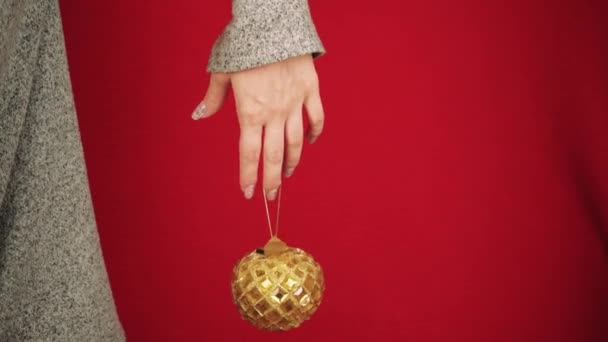 金色的圣诞舞会就像新年和圣诞节的象征 雌性手拿着一个圣诞树玩具 这个女孩给人一种节日的气氛 龙的新年象征 节日气氛 — 图库视频影像
