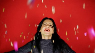 Neşeli, güzel esmer kız ellerinden konfeti üflüyor. Tatilin kutlaması. Şenlikli yeni yıl atmosferi. Eğlenceli bir etkinlik. Noel konsepti