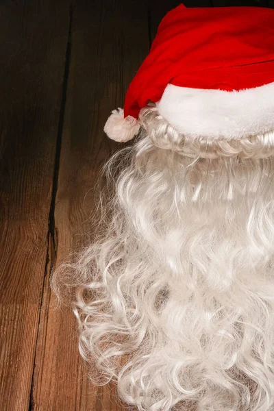Santa hat and beard on a wooden background. Symbolism of New Year's holidays. Christmas and new year concept. Change of clothes, change of image