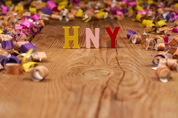 Happy New Year lettering, gift box with confetti on wooden background. Festive atmosphere. New year concept