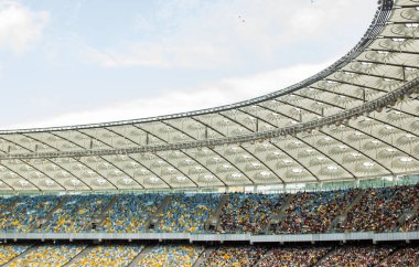 futbol stadyumu içinde görünümü. futbol sahası, boş tribünler, taraftar kalabalığı, gökyüzüne karşı bir çatı.