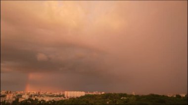 Şehirdeki bir yerleşim yeri üzerinde fırtına bulutları. Şehrin üzerinde gökkuşağı. Yaz akşamları şehir ve şehir parkının üzerinde gökkuşağı olan büyük bulut