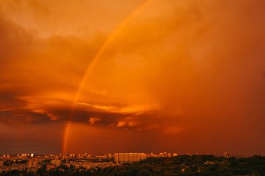 Binaların üzerindeki gökkuşağı manzarası. Turuncu gökyüzü