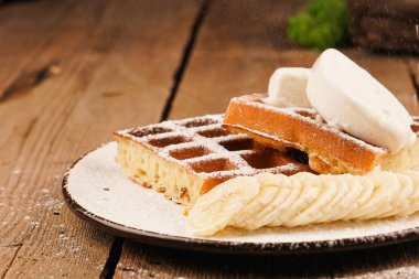 Tahta masada Belçika waffle 'ı. Beyaz tabakta Belçika waffle 'ı. Üstü pudra şekerli. Waffle tabakta. Dondurma sosu. Yemek pişirme süreci. Waffle üzerine muz ekliyorum. Ev yapımı basit hamur işleri.