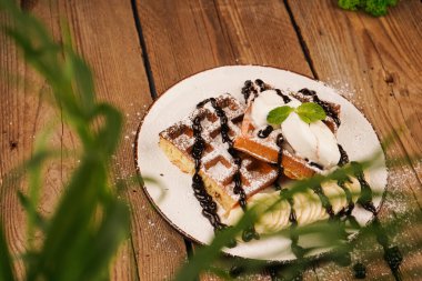 Yemek pişirme süreci. Dondurma ile servis edilir. Üstünde muz, dondurma ve çikolata olan Belçika waffleları. Tatlı gözlemeler. Çay saati için lezzetli bir tatlı. Tatlının üstüne nane.