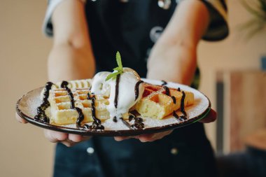 Çay saati için lezzetli bir tatlı. Yemek pişirme süreci. Tatlı ikram ediyorum. Muzlu, dondurmalı ve çikolatalı Belçika waffleları. Tatlı gözlemeler. Ellerinde waffle tutan kız. Dondurma ile servis edilir.