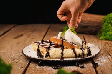 Dondurma ile servis edilir. Üstünde muz, dondurma ve çikolata olan Belçika waffleları. Tatlı gözlemeler. Çay saati için lezzetli bir tatlı. Tatlının üstüne nane şekeri. Yemek pişirme süreci