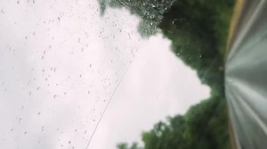 Yağmur damlalarıyla döşenmiş bir pencereden bir aracın içini görmek. Bardakta yağmur damlaları vardı, sanki yeni bir sağanak yağmış gibi. Dikey görünüm