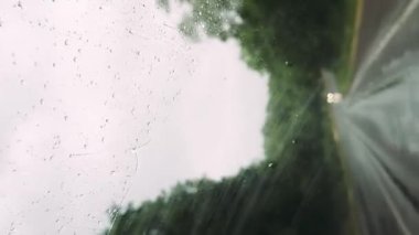 Yağmur damlalarıyla döşenmiş bir pencereden bir aracın içini görmek. Bardakta yağmur damlaları vardı, sanki yeni bir sağanak yağmış gibi. Dikey görünüm
