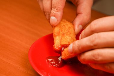 Tavuk nugget yiyen adam. Tavuk nugget tutuyorum. Ketçaplı tavuk nugget. Fast food. Abur cubur. Sağlıksız bir yaşam tarzı. Kalori. Obezite. Amerikan yemekleri.