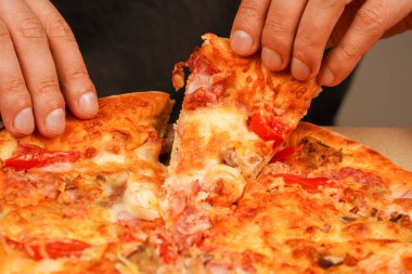 Restoran reklamı. Lezzetli peynirli pizza. - Pizza. Sağlıksız yiyecekler. Abur cubur. Yağlı yemek. Fast food siparişi. Paket servis kavramı. Pizzacıda lezzetli yemekler. Elle pizza dilimi alıp, manzarayı kapatın.