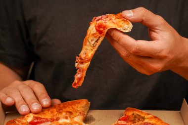 Paket servis kavramı. Fast food siparişi. Restoran reklamı. Lezzetli peynirli pizza. - Pizza. Sağlıksız yiyecekler. Abur cubur. Yağlı yemek. Pizzacıda lezzetli yemekler. Elle pizza dilimi alıp, manzarayı kapatın.