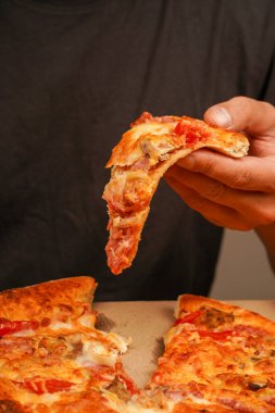 Restoran reklamı. Lezzetli peynirli pizza. - Pizza. Sağlıksız yiyecekler. Abur cubur. Yağlı yemek. Fast food siparişi. Paket servis kavramı. Pizzacıda lezzetli yemekler. Elle pizza dilimi alıp, manzarayı kapatın.