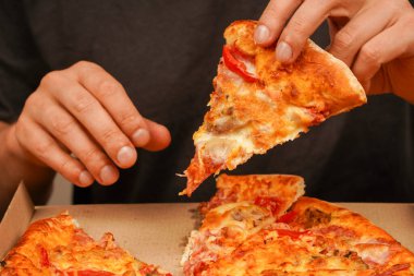 Abur cubur. Yağlı yemek. Fast food siparişi. Restoran reklamı. Lezzetli peynirli pizza. - Pizza. Sağlıksız yiyecekler. Paket servis kavramı. Pizzacıda lezzetli yemekler. Elle pizza dilimi alıp, manzarayı kapatın.