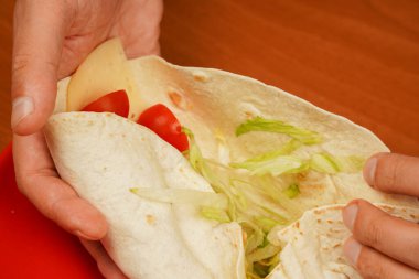 Tavuklu dürüm açıldı. Kızarmış tavuk eti ve sebzeli tortilla dürümü, yakın çekim. Shawarma domatesi, salatalık, soğan, marul ve tavuk eti. Fast food. Abur cubur. Yemek yiyorum. Yiyecekler. Lezzetli