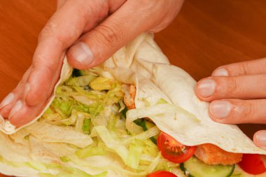 Tavuk sarması pişiriyorum. Kızarmış tavuk eti ve sebzeli tortilla dürümü, yakın çekim. Shawarma domatesi, salatalık, soğan, marul ve tavuk eti. Fast food. Abur cubur. Yemek yiyorum. Yiyecekler. Lezzetli