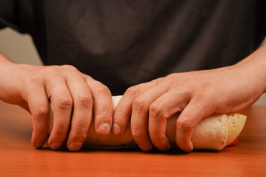 Fast food. Abur cubur. Yemek yiyorum. Yiyecekler. Lezzetli. Tavuk dürümü hazırlanıyor. Kızarmış tavuk eti ve sebzeli tortilla dürümü, yakın çekim. Shawarma domatesi, salatalık, soğan, marul ve tavuk eti.