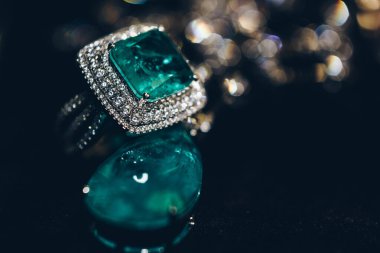 Zümrütler mücevherlere yakın çekim yapar. Yeşil zümrüt ve elmas değerli taşlı güzel küpeler. Siyah arka planda, lüks kadın mücevherleri.