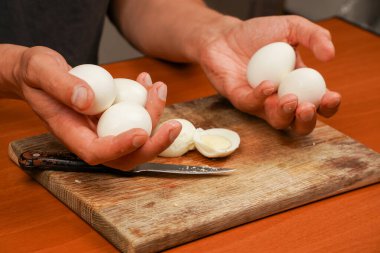 Sağlıklı yiyecekler. Masada haşlanmış tavuk yumurtası var, yakın plan. Protein. Sporcu yemeği. Yemek hazırlıyorum. Yatay fotoğraf. Vejetaryen. Tahta üzerinde tavuk yumurtası tutan adam. Haşlanmış yumurta.