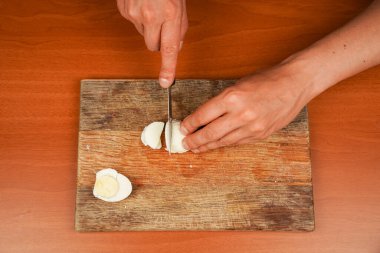 Horizontal photo. Board with boiled chicken eggs on table, closeup. Preparing food. Healthy food. Protein. Sportsmens food. Vegetarian. Mans hands cut a chicken egg with a knife on a wooden board clipart