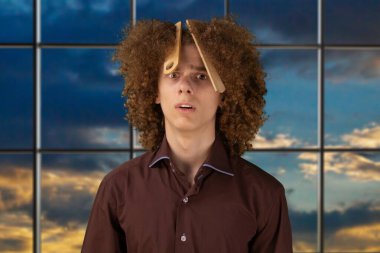 Erkek saç bakım konsepti. Genç Avrupalı adam uzun kıvırcık saçlarını saç fırçasıyla tarıyor. El sallayan saçlarını önemsiyor ve şekillendiriyor. Stüdyonun arka planında duruyorum.