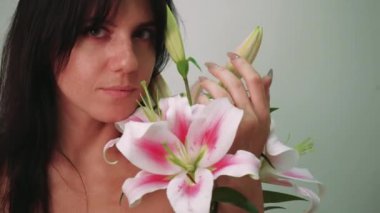 Lily Flower ile Kadın Güzellik Yüzü Portresi. Pürüzsüz cilt makyajlı manken kız. Spa Bakımı ve Rahatlatıcı Kozmetoloji Konsepti. Bej Arkaplan
