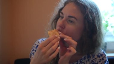 Yumuşak doğal ışık, o anın sakin ve samimi atmosferini arttırır. Mavi beyaz elbiseli genç bir kadın, kapalı bir masada otururken bir yudum kahve alır.