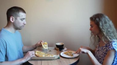 Genç bir çift rahat bir kafede pizza ve kahve paylaşarak gündelik bir yemeğin tadını çıkarıyor. Rahatlamış atmosfer lezzetli yiyecek ve içecekler üzerinde sosyalleşmek için idealdir.