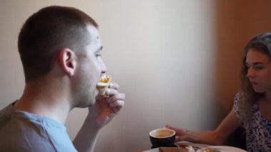 İki arkadaş ya da bir çift küçük bir kafede kahve ve pizza paylaşıyor. İyi yemek ve sohbetle dolu sıradan yemek anı, sıcak ve davetkar bir birliktelik ve zevk sahnesi yaratır.