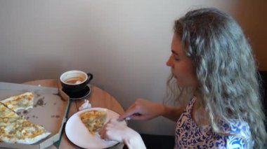 İletişim sürecinde gülümseyen genç bir kadın. Lokantada olumlu duyguları olan bir kız yemek ve içeceklerle dolu bir masada oturuyor.