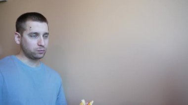 Hareketli bir kafede, genç bir adam coşkuyla içerken bir dilim pizzayı hevesle yer. Yemeği beğenmesi, bu anı canlı ve çekici kılıyor.