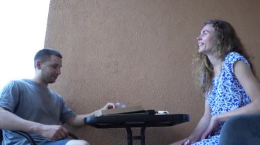 Kıvırcık saçlı Avrupalı bir kız bir erkekle pizza yiyor. Arkadaki adam.