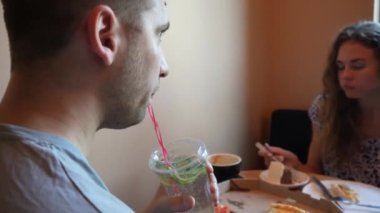 İki kişi, bir erkek ve bir kadın, rahat bir masada oturup kahvenin tadını çıkarıyor ve neşeyle konuşuyorlar. Kafenin aydınlık ortamı birlikte geçirdikleri mutlu anlara sıcaklık katıyor.