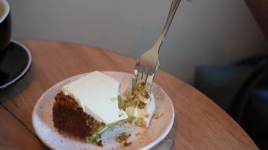 Ahşap masada üzerinde pasta olan bir tatlı tabağı var. Beyaz kremalı bir parça kek kırılmış ve içine çatal yapışmış.