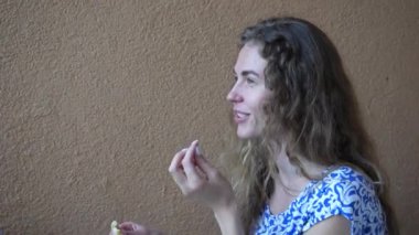 Elinde bir parça yemek tutan mutlu, güzel bir kadın. Sarı arka planda bir kız pizza yiyor, yakın plan. Kız bir kafede dinleniyor.