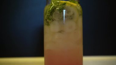 Mavi arka planda bardakta taze yaz kokteyli. Turunçgiller ve buzla dolu bir bardakta pembe su