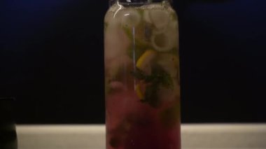 Mavi arka planda bardakta taze yaz kokteyli. Turunçgiller ve buzla dolu bir bardakta pembe su