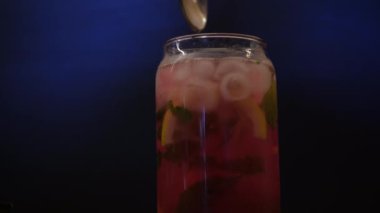 Mavi arka planda bardakta taze yaz kokteyli. Turunçgiller ve buzla dolu bir bardakta pembe su
