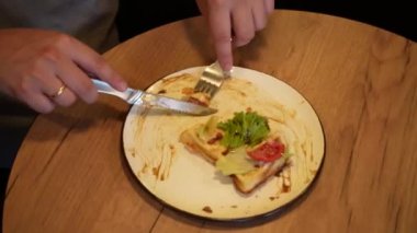 Odak noktası eller, tabaklar ve parlak yiyecekler. Sıcak bir atmosferde sağlıklı yiyecekler sergiliyorlar. Bir adam taze sebzeler, domatesler ve taze Belçika wafflelarından oluşan lezzetli bir tabak keser.