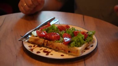 Odak noktası eller, tabaklar ve parlak yiyecekler. Sıcak bir atmosferde sağlıklı yiyecekler sergiliyorlar. Bir adam taze sebzeler, domatesler ve taze Belçika wafflelarından oluşan lezzetli bir tabak keser.