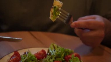 Odak noktası eller, tabaklar ve parlak yiyecekler. Sıcak bir atmosferde sağlıklı yiyecekler sergiliyorlar. Bir adam taze sebzeler, domatesler ve taze Belçika wafflelarından oluşan lezzetli bir tabak keser.