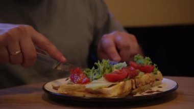 Tabak, rahat bir atmosferde sağlıklı yiyecekleri ön plana çıkaran ahşap bir masada servis ediliyor. Yakından bakınca, çatal ve bıçakla taze domates salatası yiyen bir adam görülüyor.