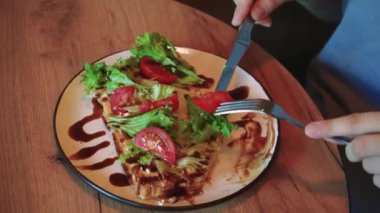 Genç bir kadın sakince pencerede öğle yemeği yiyor, sebzeli sağlıklı bir yemeğin tadını çıkarıyor. İçerde sakin bir ortamda öğle yemeği yiyen bir kadının yakın çekimi.